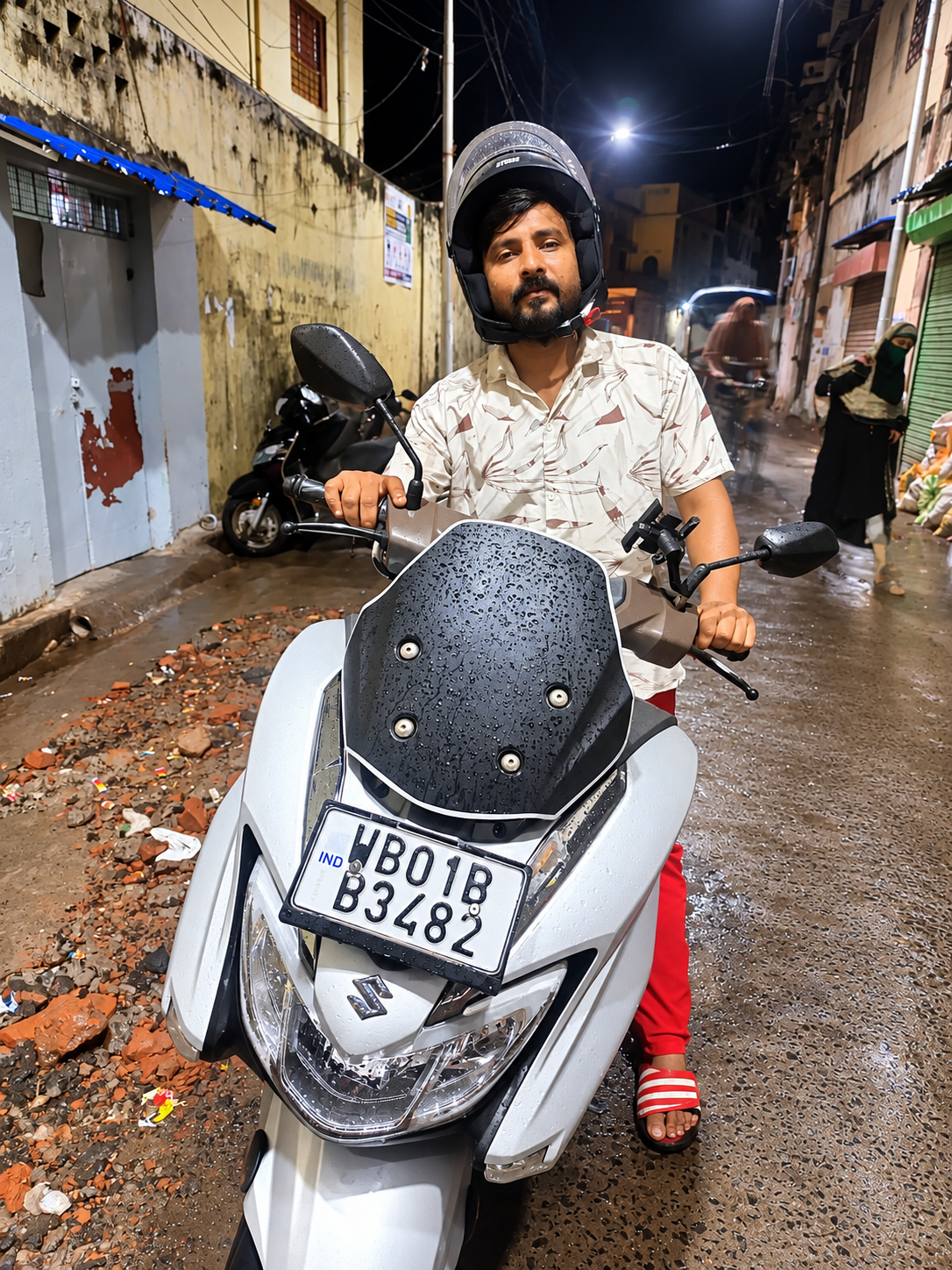 A man with a two-wheeler on a rainy Kolkata street, illustrating the livelihood initiative